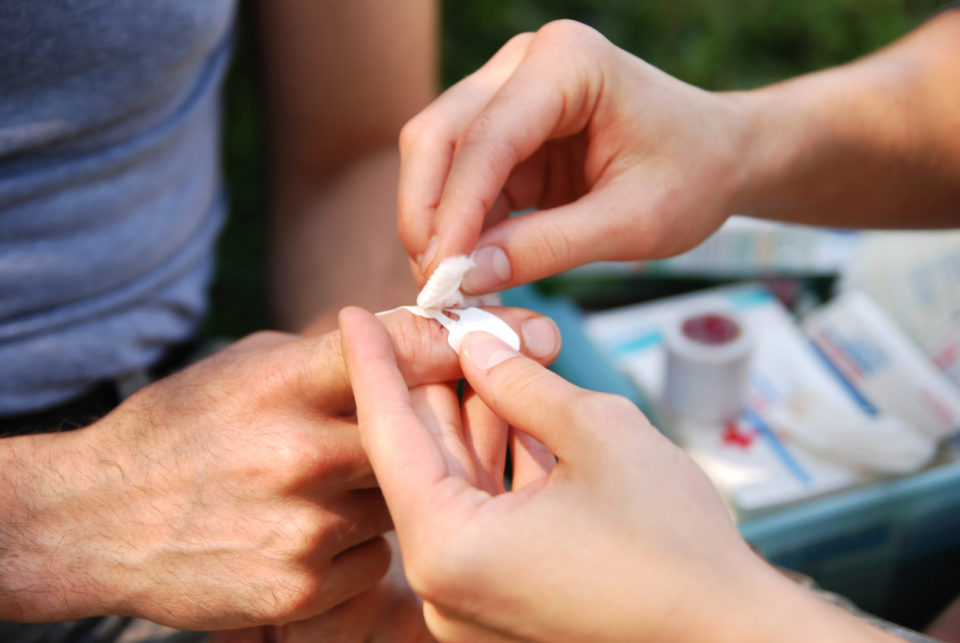 A woman helps bandage a cut in a man's finger.