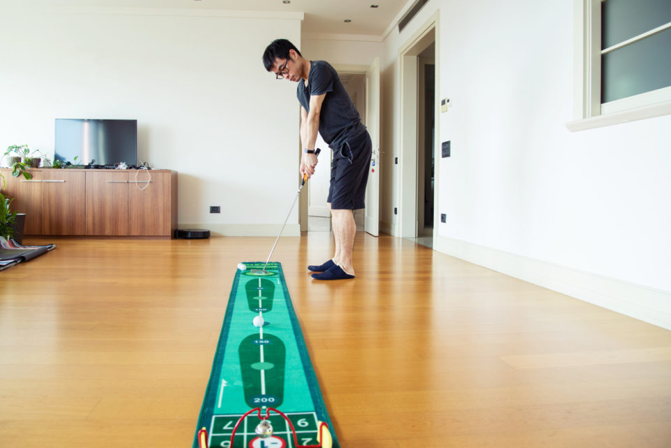 A mid adult man playing mini-golf at home during the 2020 pandemic lockdown.