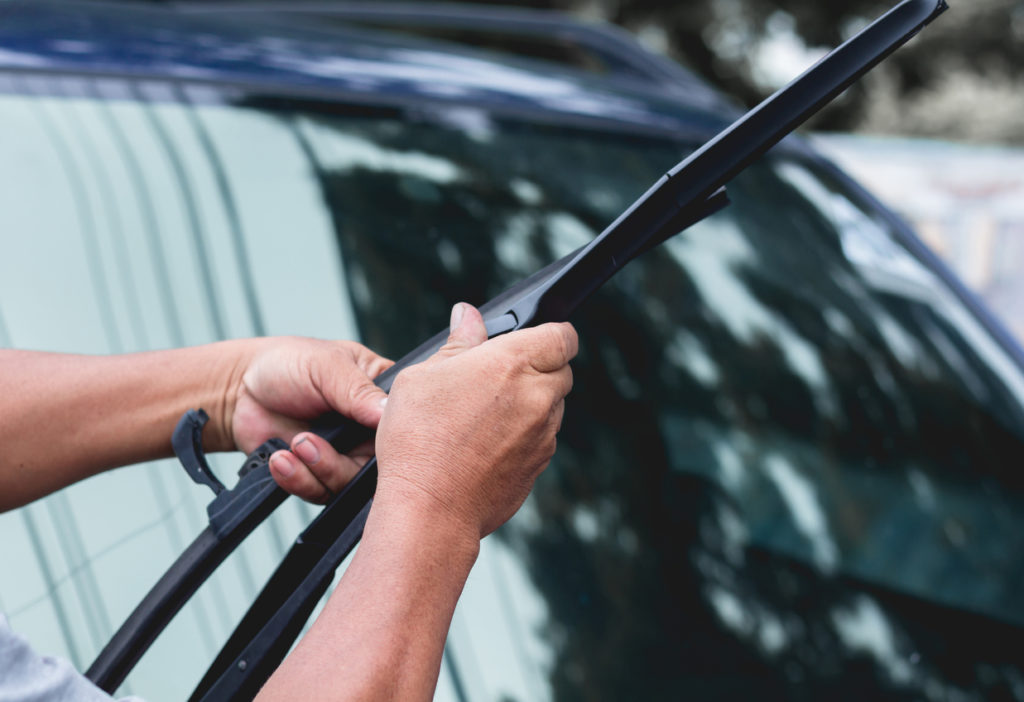Mechanic replace windshield wipers on car.