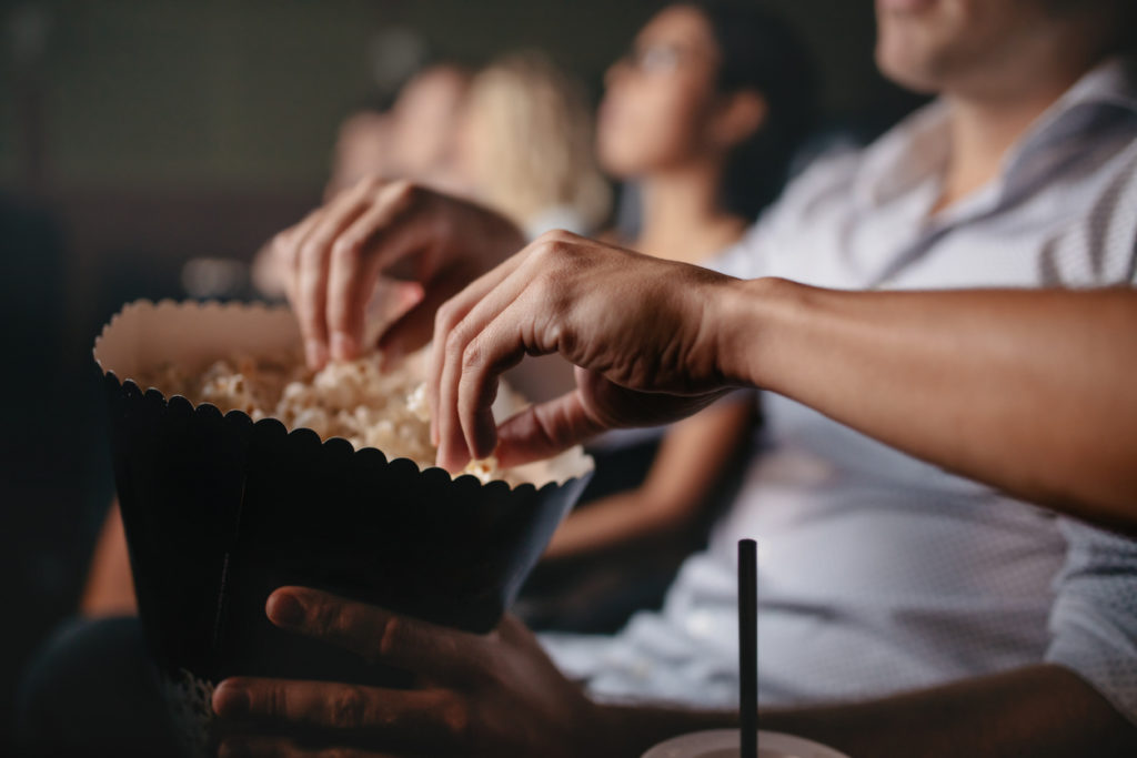 Young people eating popcorn in movie theater