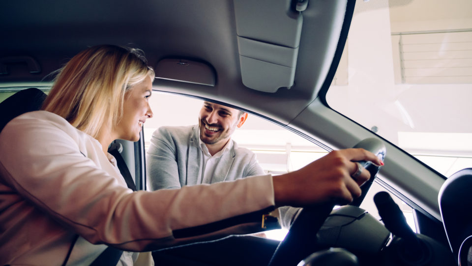 Woman buying a car in dealership sitting in her new auto