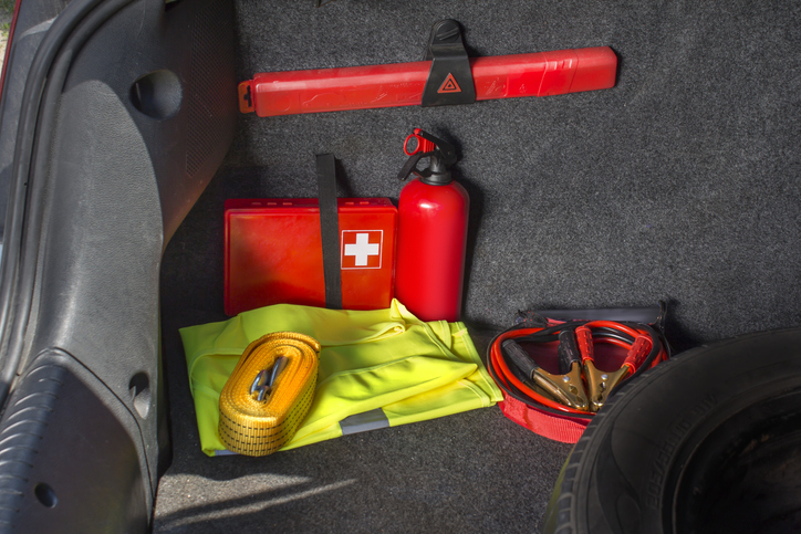 The interior of the trunk of the car in which there is a first aid kit, fire extinguisher, warning triangle, reflective vest, starter cables and tow rope