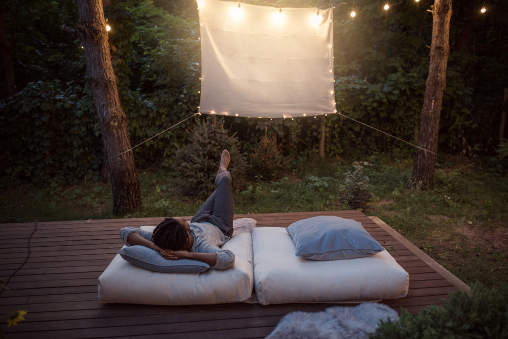 Man sitting outside looking at a projector screen.