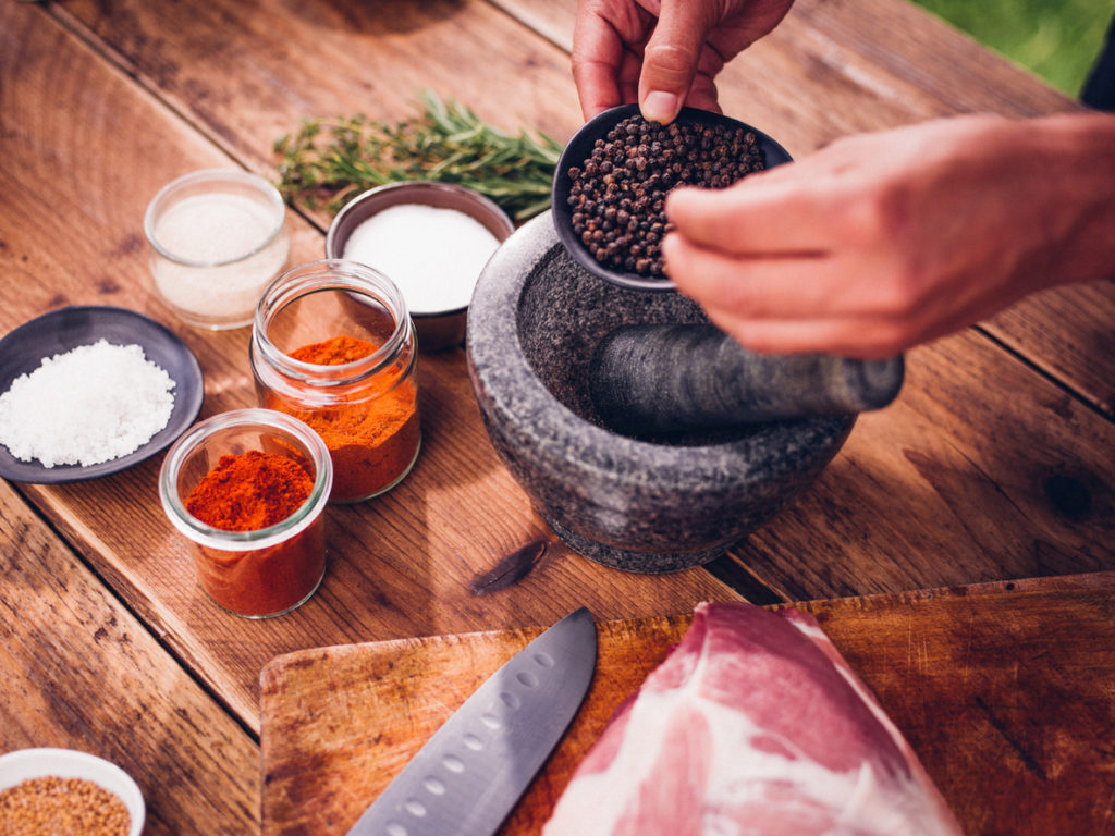 Black peppercorns being put into a mortar and pestle