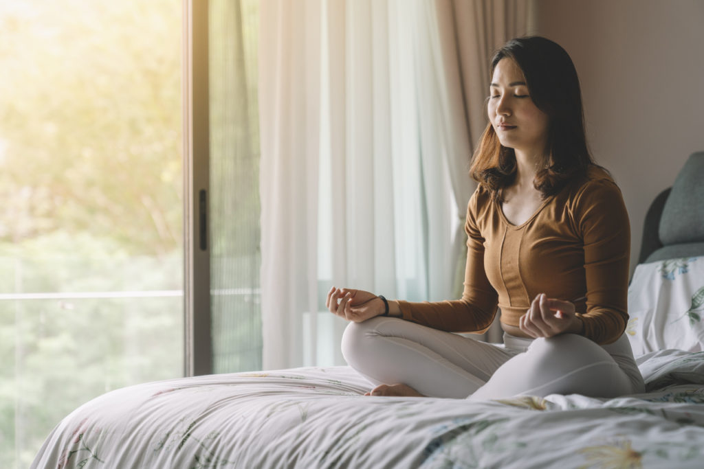 woman meditating on her bed