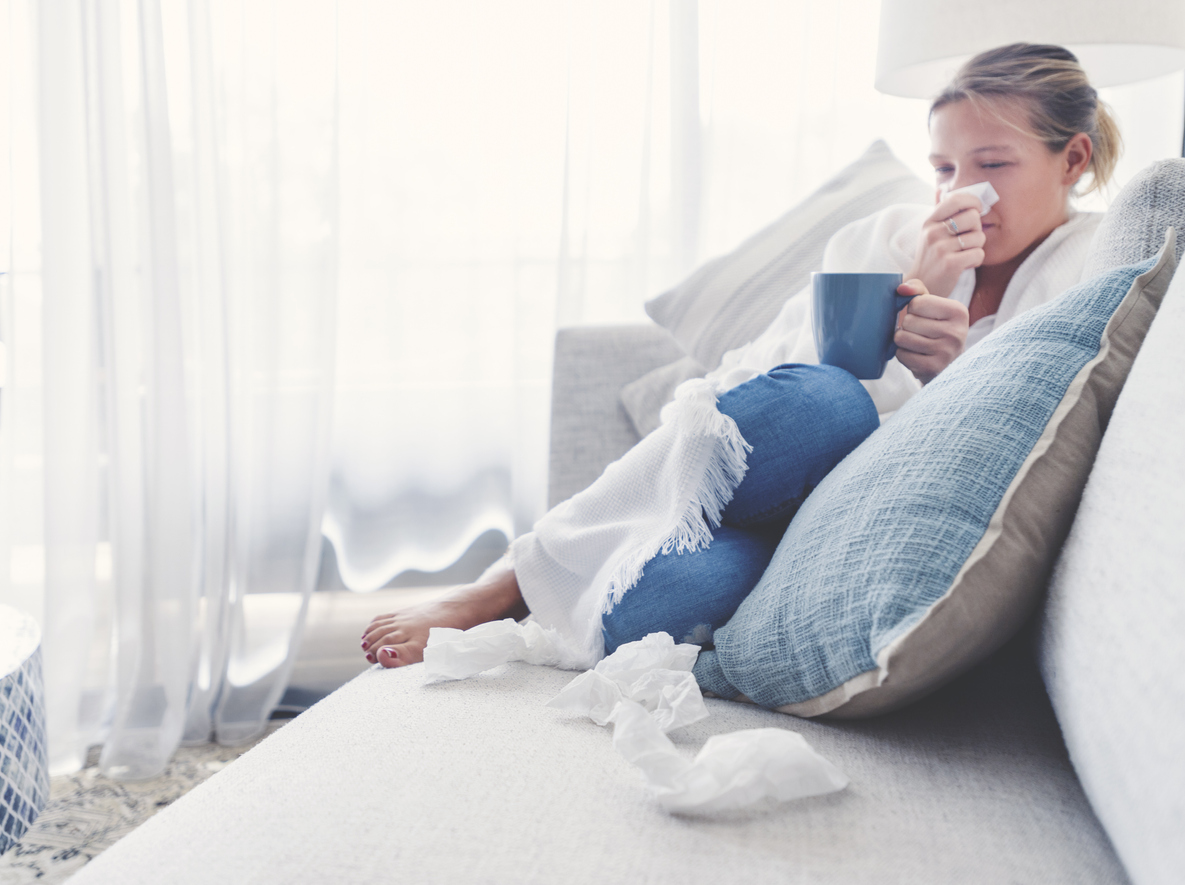 Woman sitting on the sofa with a cold, flu or allergy.