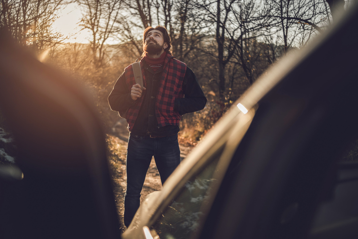A photo of a strong man walking towards his car, finishing work in the woods and calmly returning to his warm log cabin.
